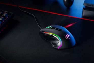 A gaming mouse glowing RGB on a black mousepad.