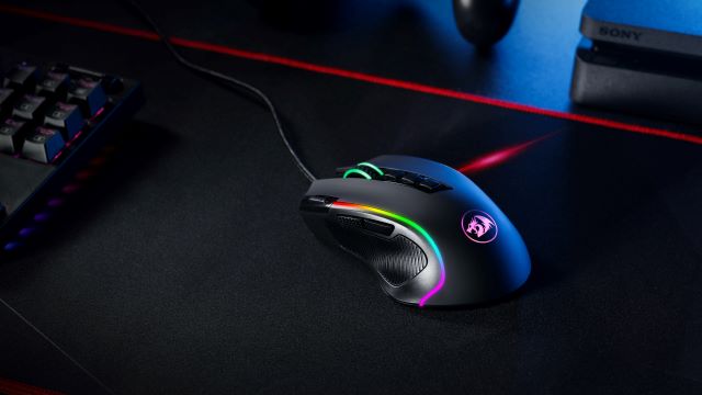 A gaming mouse glowing RGB on a black mousepad.
