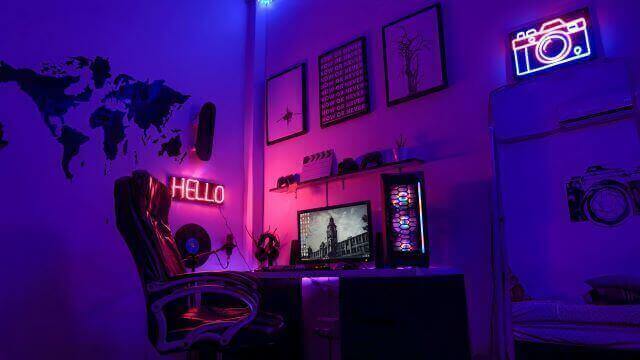A gaming room with gaming desktop under the glowing RGB lighting