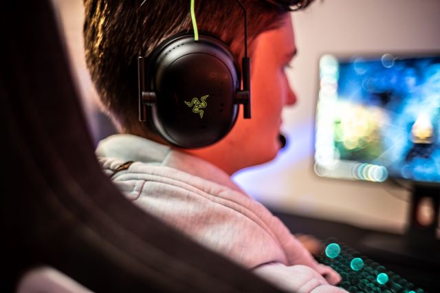 A gamer playing games putting on a Razer Headphone